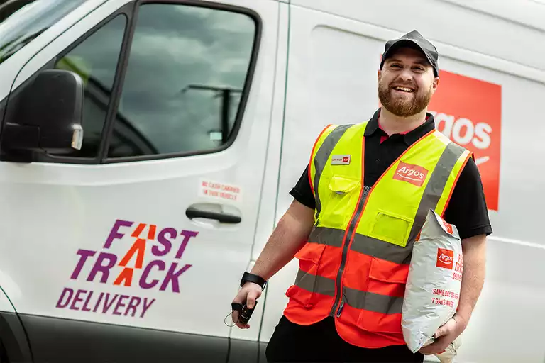 Delivery person in a high-visibility vest smiling in front of a Fast Track Delivery van.